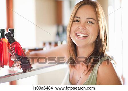 Picture - Woman holding vinegar bottle in grocery. Fotosearch