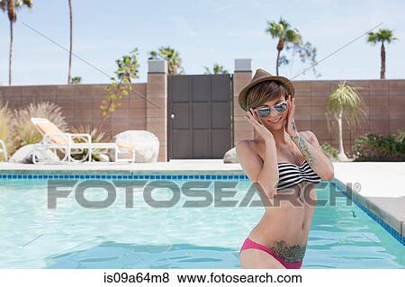 Stock Photo - Woman in bikini standing by pool. Fotosearch