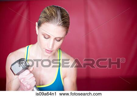 Stock Image - Woman lifting weights in gym. Fotosearch