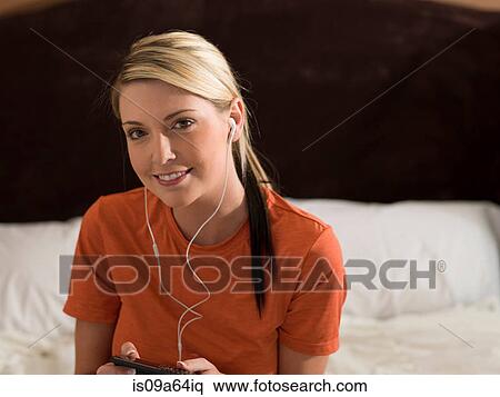 Woman listening to earphones on bed View Large Photo Image Stock Photography - Woman listening to earphones on bed. Fotosearch