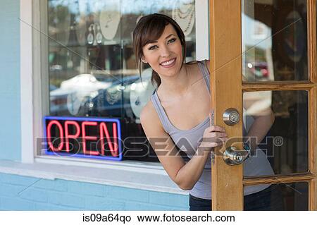 Picture - Woman peeking out front door of store. Fotosearch