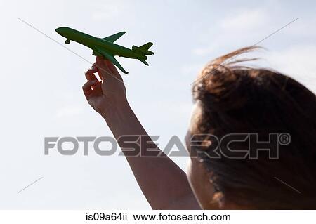 Stock Image - Woman playing with toy airplane. Fotosearch