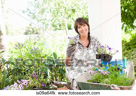 Stock Image - Woman potting plants outdoors. Fotosearch