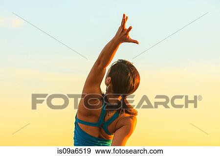 Stock Photo - Woman practicing yoga at sunset. Fotosearch