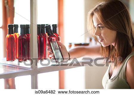 Woman reading vinegar bottle in grocery View Large Photo Image Stock Image - Woman reading vinegar bottle in grocery. Fotosearch