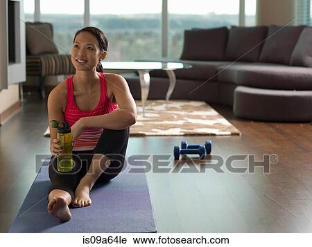 Woman resting on yoga mat in living room View Large Photo Image Stock Image - Woman resting on yoga mat in living room. Fotosearch