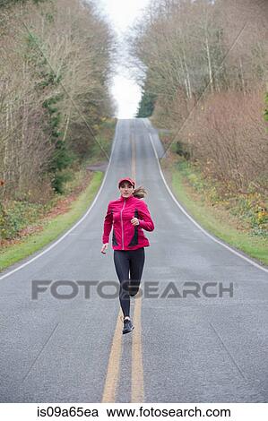 Stock Image - Woman running on rural road. Fotosearch