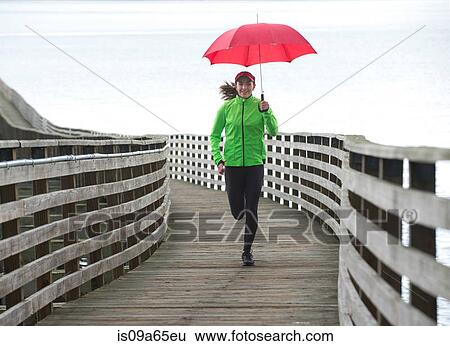 Stock Photograph - Woman running under umbrella. Fotosearch