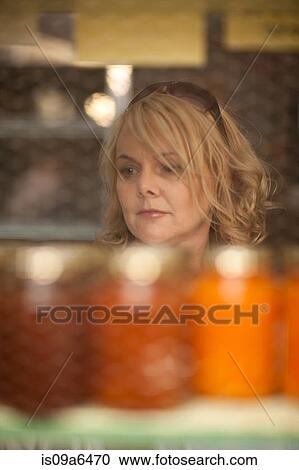 Stock Image - Woman shopping for jam in grocery. Fotosearch