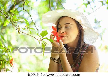 Picture - Woman smelling flower in park. Fotosearch