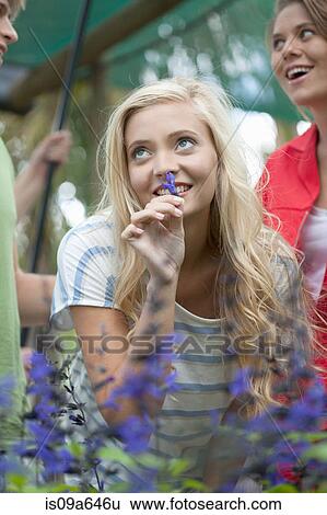 Stock Photograph - Woman smelling plants outdoors. Fotosearch
