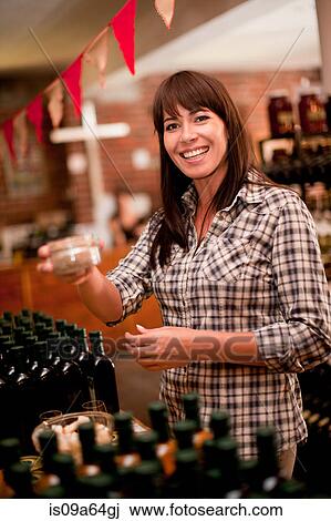 Stock Image - Woman smelling preserves in grocery. Fotosearch