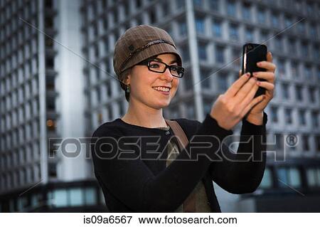 Stock Photo - Woman taking picture with cell phone. Fotosearch