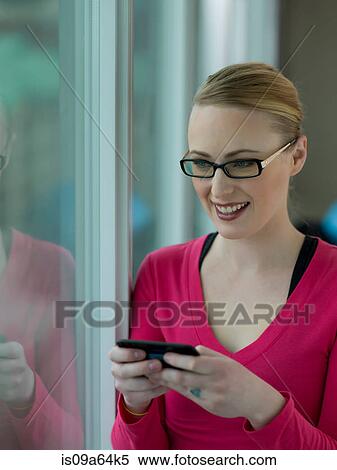 Woman using cell phone by window View Large Photo Image Stock Photography - Woman using cell phone by window. Fotosearch