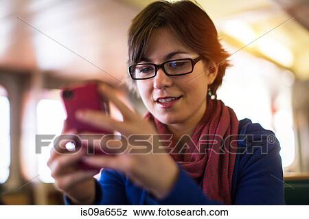 Stock Photo - Woman using cell phone on bench. Fotosearch