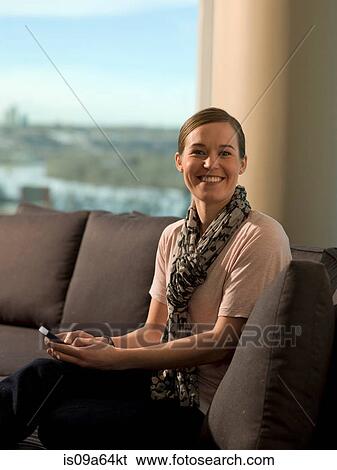 Stock Photograph - Woman using cell phone on sofa. Fotosearch
