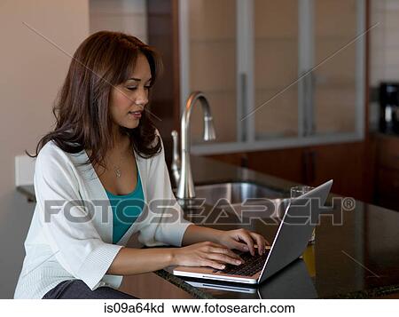 Woman using laptop at counter View Large Photo Image Stock Image - Woman using laptop at counter. Fotosearch