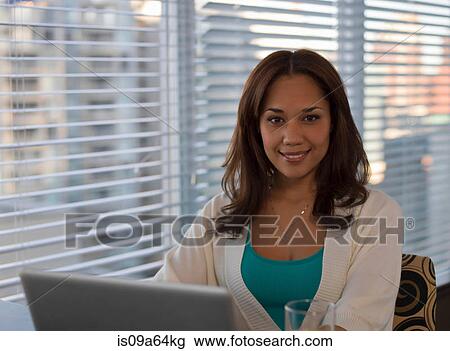 Stock Image - Woman using laptop at desk. Fotosearch