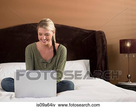 Stock Photo - Woman using laptop on bed. Fotosearch