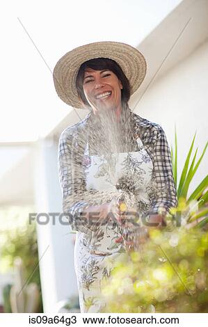Stock Image - Woman watering plants in garden. Fotosearch