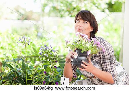 Stock Image - Woman with potted plant in garden. Fotosearch