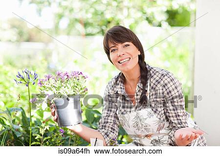 Stock Image - Woman with potted plant in garden. Fotosearch