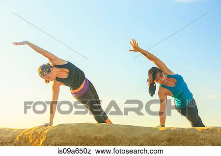 Women practicing yoga on rock formation View Large Photo Image Stock Photo - Women practicing yoga on rock formation. Fotosearch