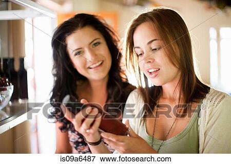 Stock Photo - Women reading vinegar bottle in grocery. Fotosearch