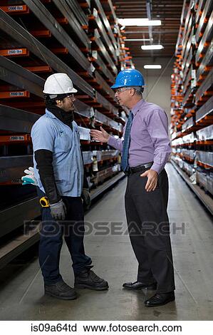 Stock Image - Worker and businessman in metal plant. Fotosearch