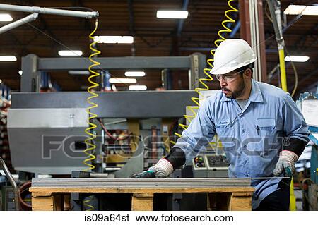Worker examining product in metal plant View Large Photo Image Stock Photograph - Worker examining product in metal plant. Fotosearch