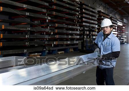 Stock Image - Worker holding metal in plant. Fotosearch