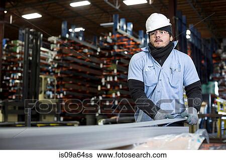Stock Photograph - Worker holding sheet in metal plant. Fotosearch