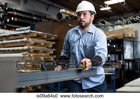 Stock Image - Worker measuring in metal plant. Fotosearch