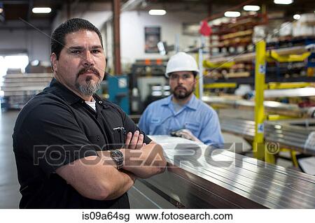 Stock Image - Worker standing in metal plant. Fotosearch