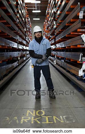 Stock Image - Worker standing in metal plant. Fotosearch