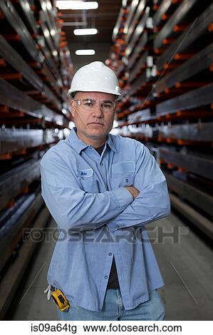Stock Image - Worker standing in metal plant. Fotosearch