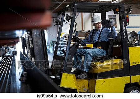 Stock Photograph - Worker using forklift in metal plant. Fotosearch