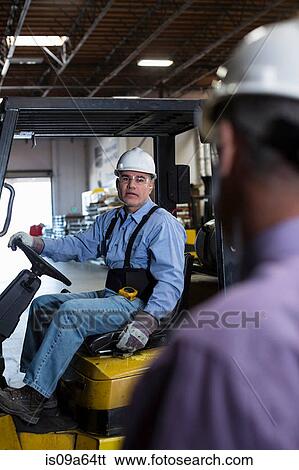 Stock Photograph - Worker using forklift in metal plant. Fotosearch