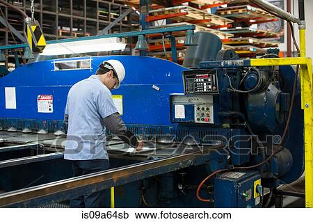 Stock Image - Worker using machinery in metal plant. Fotosearch