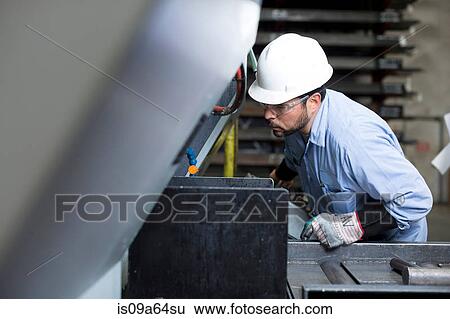 Stock Photograph - Worker using machinery in metal plant. Fotosearch