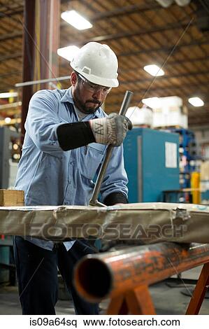 Stock Photography - Worker using machinery in metal plant. Fotosearch