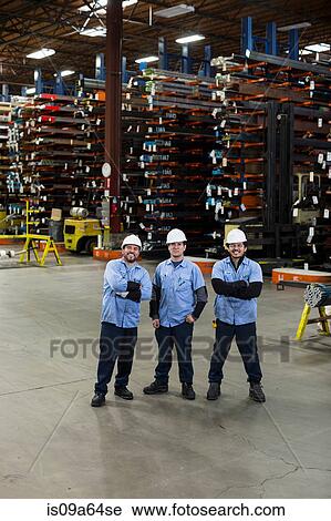 Stock Image - Workers standing in metal plant. Fotosearch
