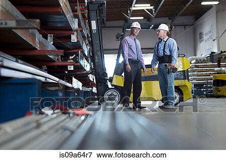 Stock Photo - Workers talking in metal plant. Fotosearch