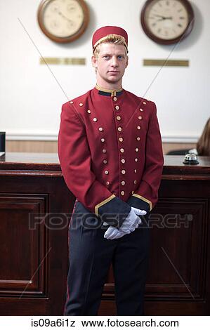 Stock Photo - Bellhop standing in hotel lobby. Fotosearch