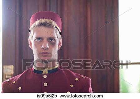 Stock Image - Bellhop with black eye in hotel lobby. Fotosearch