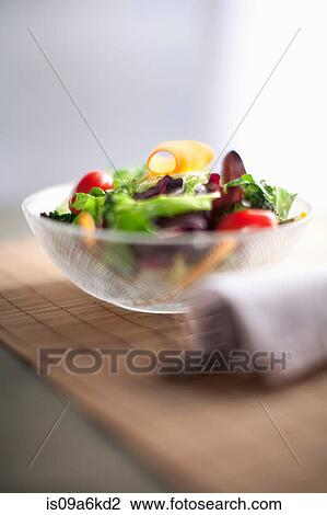 Stock Image - Bowl of salad on wooden board. Fotosearch