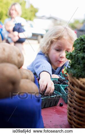 Stock Image - Boy eating fruit at farmer's market. Fotosearch