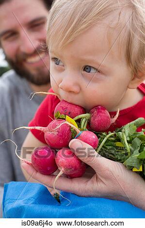 Picture - Boy eating vegetables at farmer's market. Fotosearch