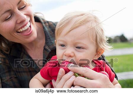 Stock Photography - Boy eating vegetables at farmer's market. Fotosearch