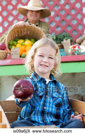 Boy holding apple at farmer's market View Large Photo Image Stock Image - Boy holding apple at farmer's market. Fotosearch